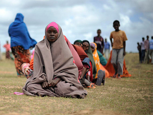 Fotografa de Portada: Un grupo de inmigrantes aguarda sentado en el suelo (foto: ONU)